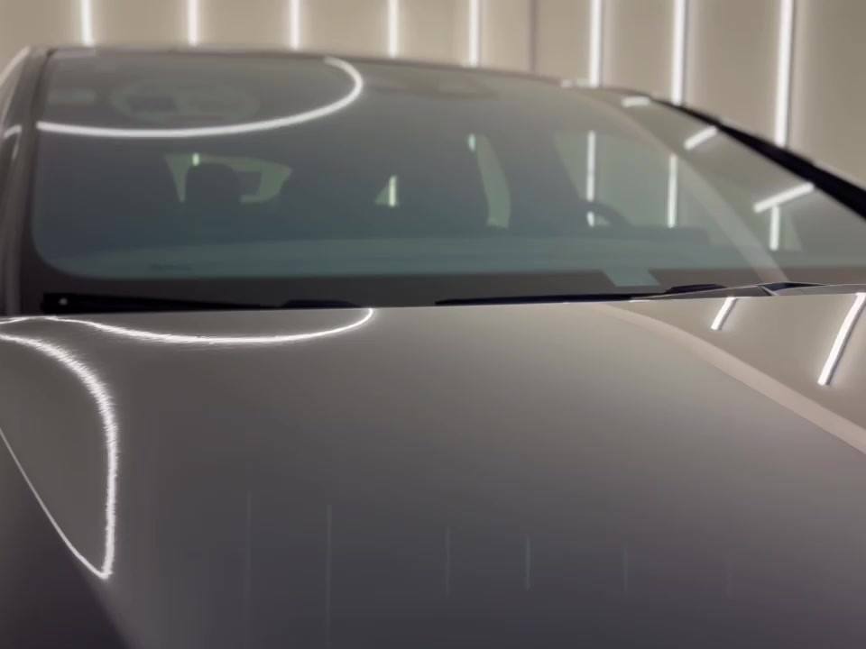 Reflejo de las luces del taller en el cofre de un Mercedes-Benz EQS